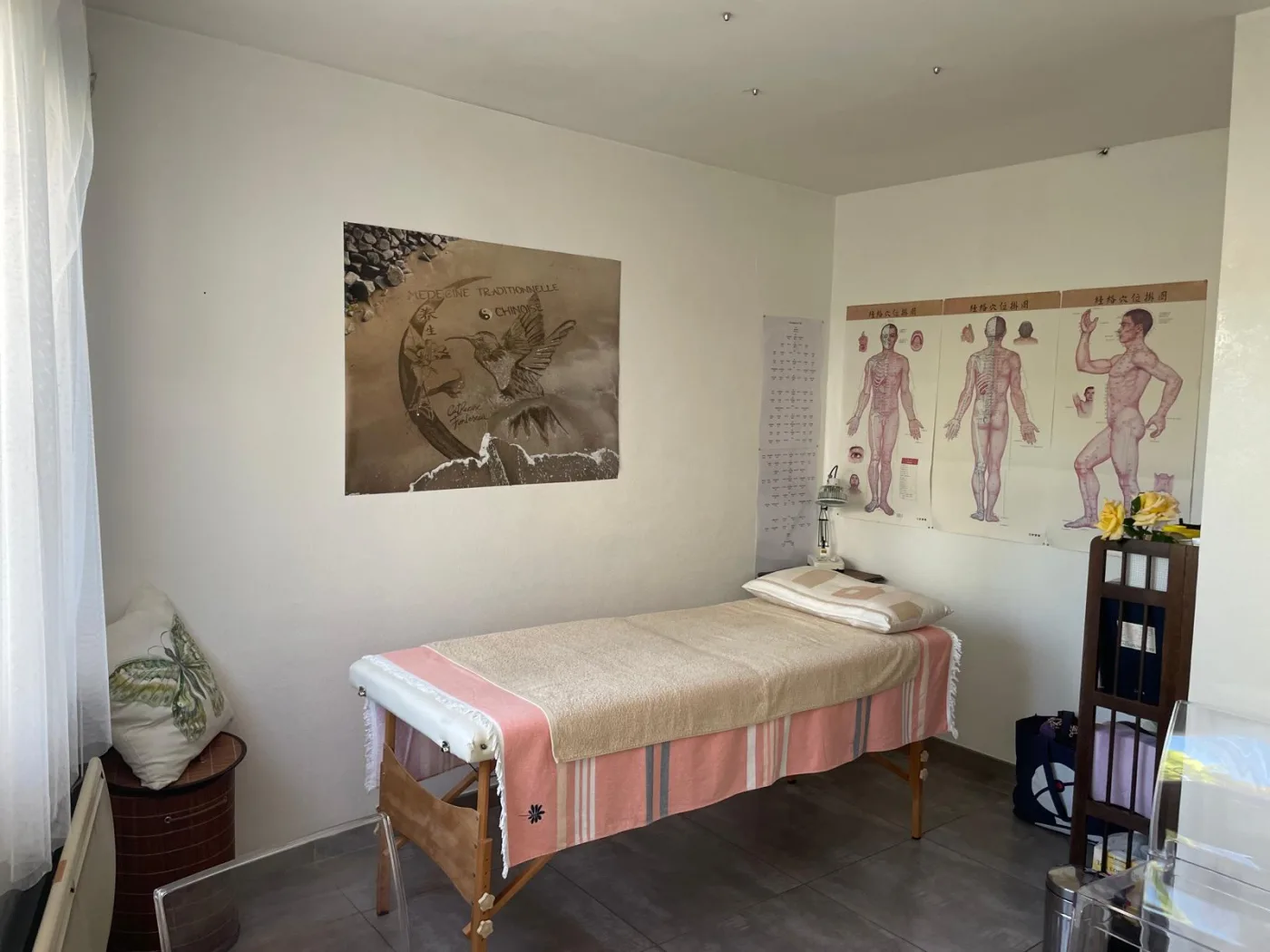 Salle de soin avec affiche colibri 'Médecine traditionnelle chinoise' signée Catherine, table et planches d'acupuncture